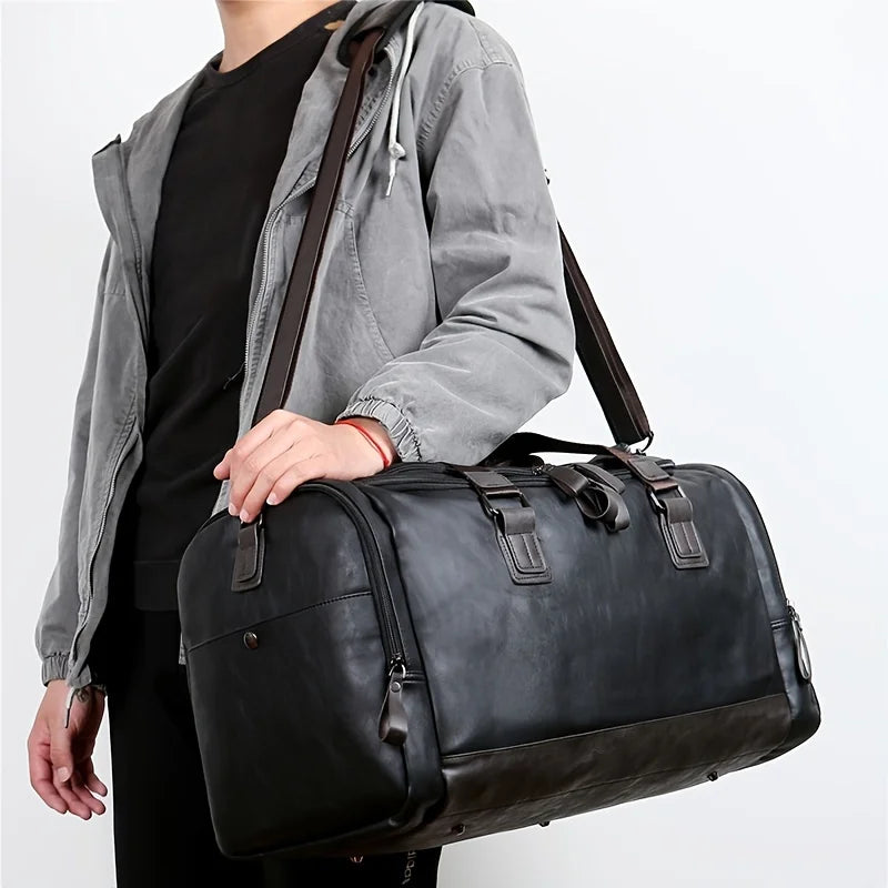 Person holding a black leather duffel bag against a white background