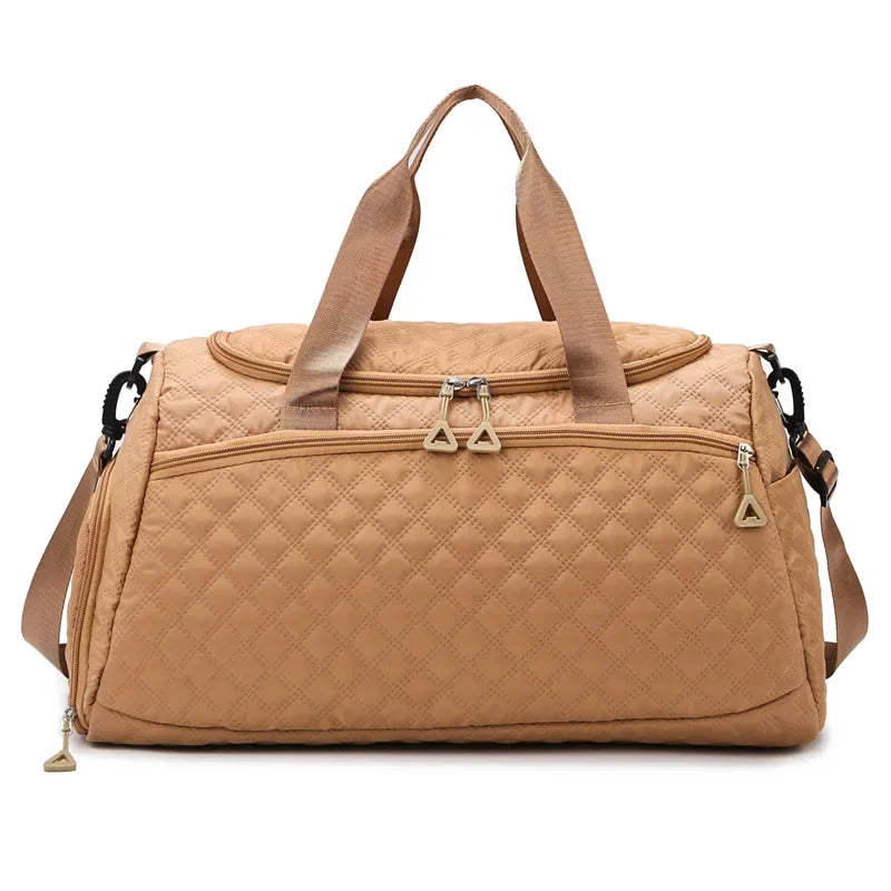 Tan quilted duffel bag with handles and zippers on a white background