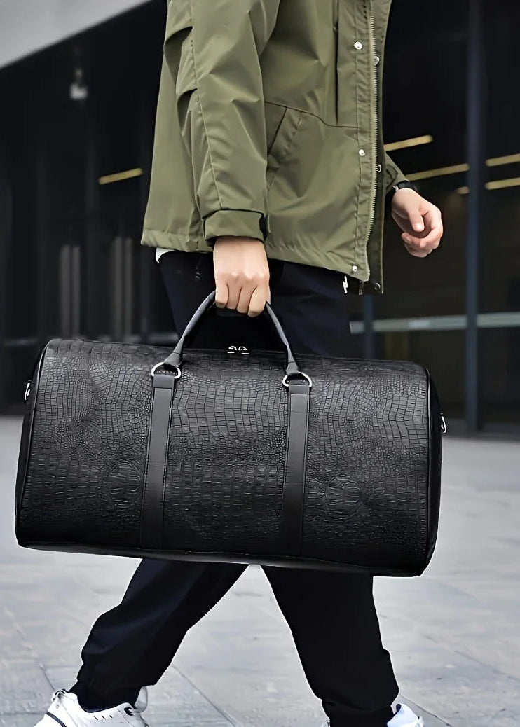Person holding a black duffel bag in an urban setting