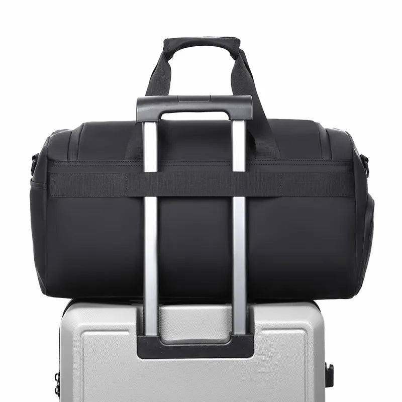 Black duffel bag on top of a silver suitcase with a white background