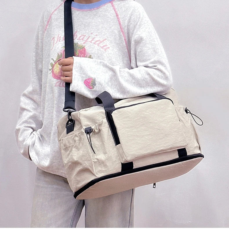 Person wearing a white sweatshirt with floral designs and a beige shoulder bag on a plain background