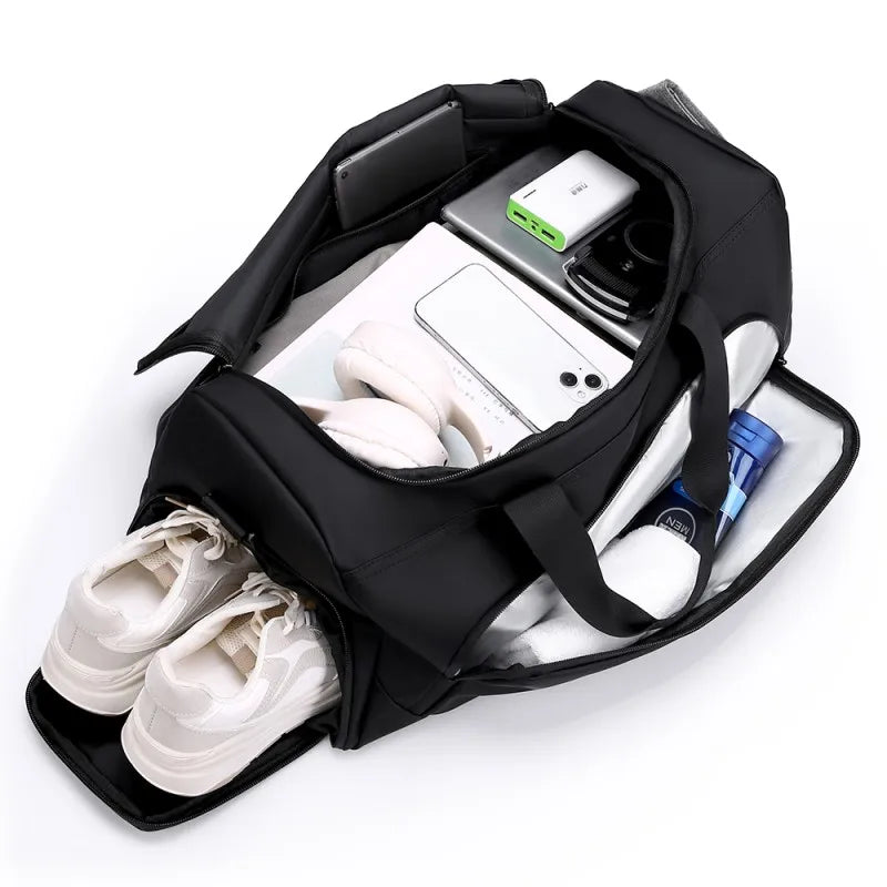 Black travel bag with compartments for shoes, electronic devices, and other items on a white background