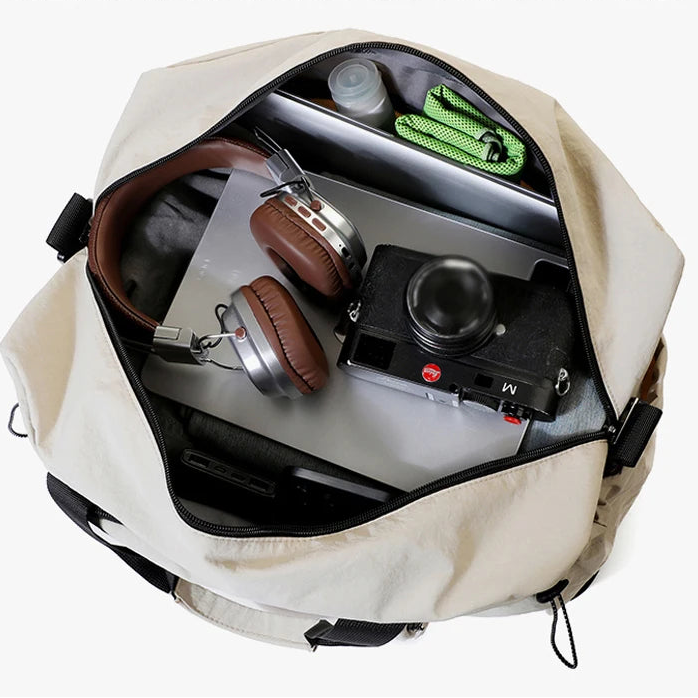 Open beige backpack with camera, headphones, and other items on a white background