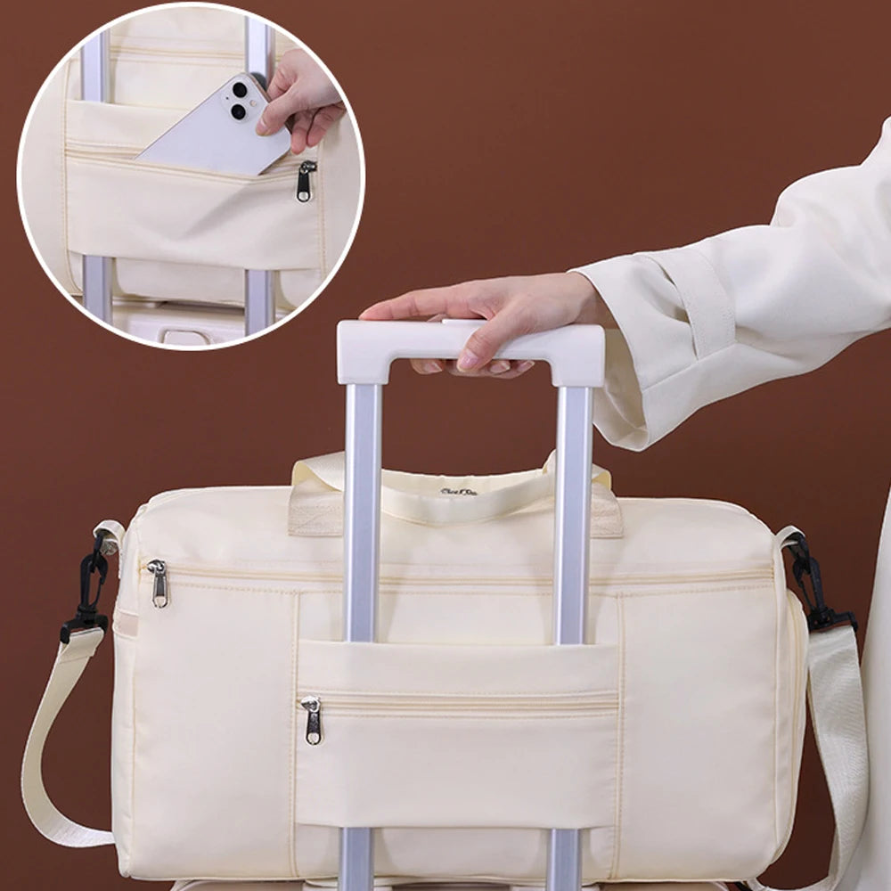 Beige travel bag with wheels being held by a hand on a brown background