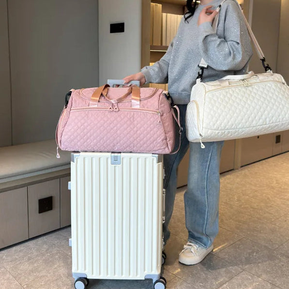 Woman with a pink quilted bag and white suitcase in an indoor setting