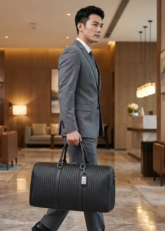 Man in a gray suit holding a black leather bag in a luxurious lobby.