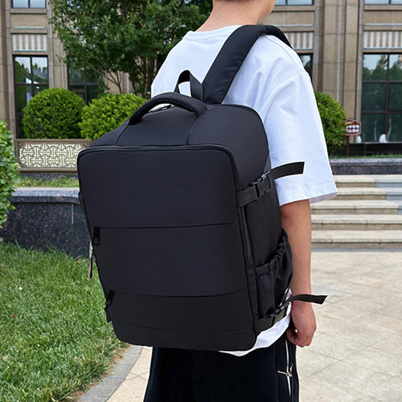 Person wearing a black backpack outdoors on a sidewalk.
