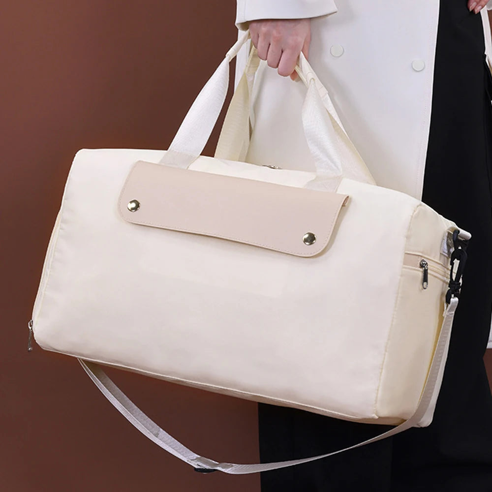 Beige duffel bag held by a person wearing a white coat against a brown background