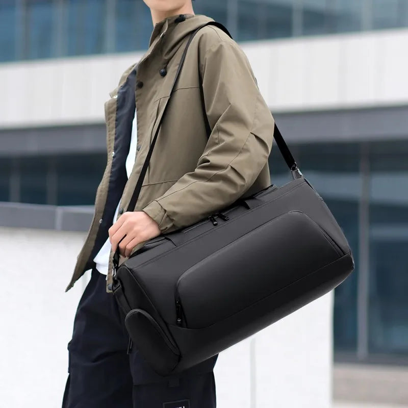 Person holding a black shoulder bag outdoors
