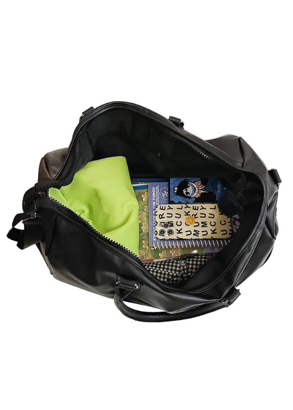 Black backpack with items including a green shirt, books, and a patterned book on a white surface.