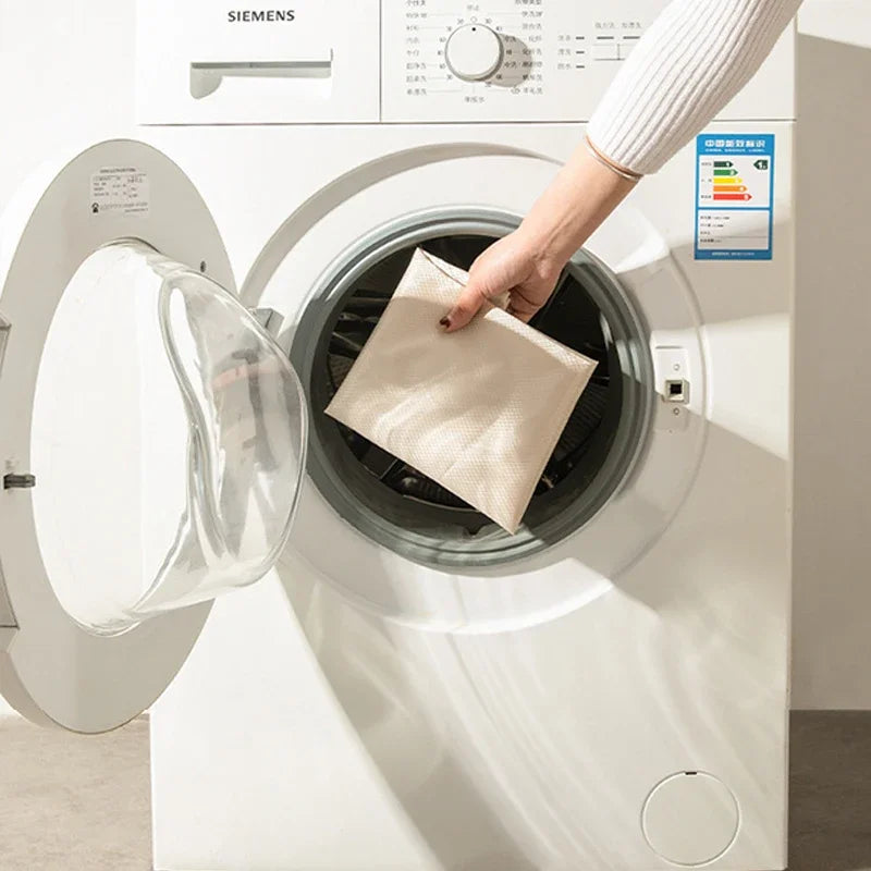 Person placing a beige towel into a Siemens washing machine.