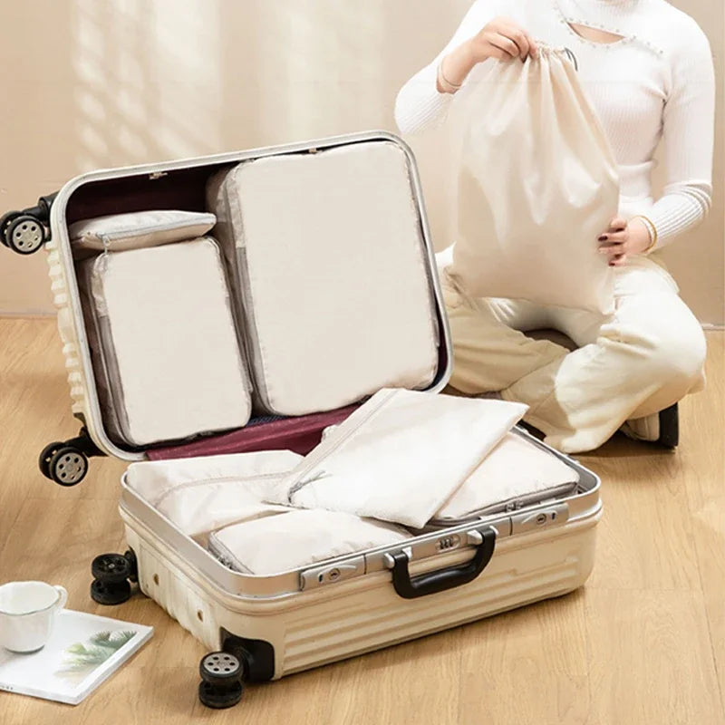 Person packing a suitcase with compression bags on a wooden floor.