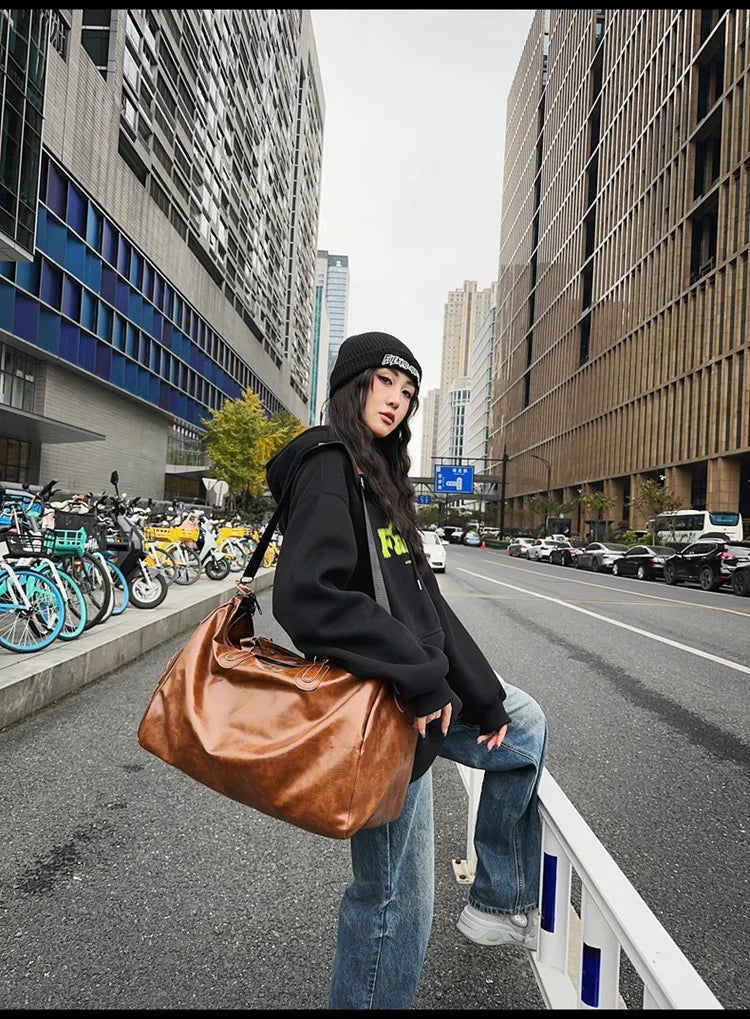 Person holding a brown bag on a city street with buildings and parked cars in the background