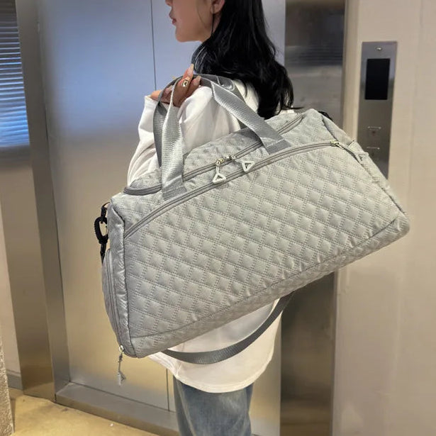 Person holding a large gray quilted bag in an elevator