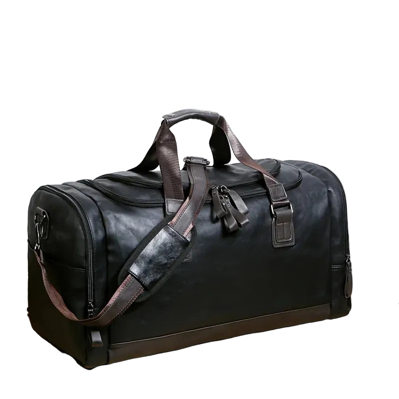 Black duffel bag with brown straps on a wooden surface