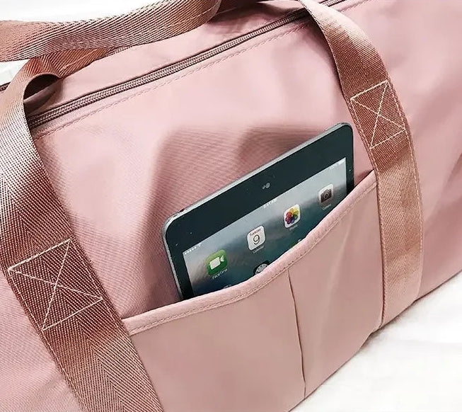 Pink duffel bag with a smartphone in a pocket on a white background