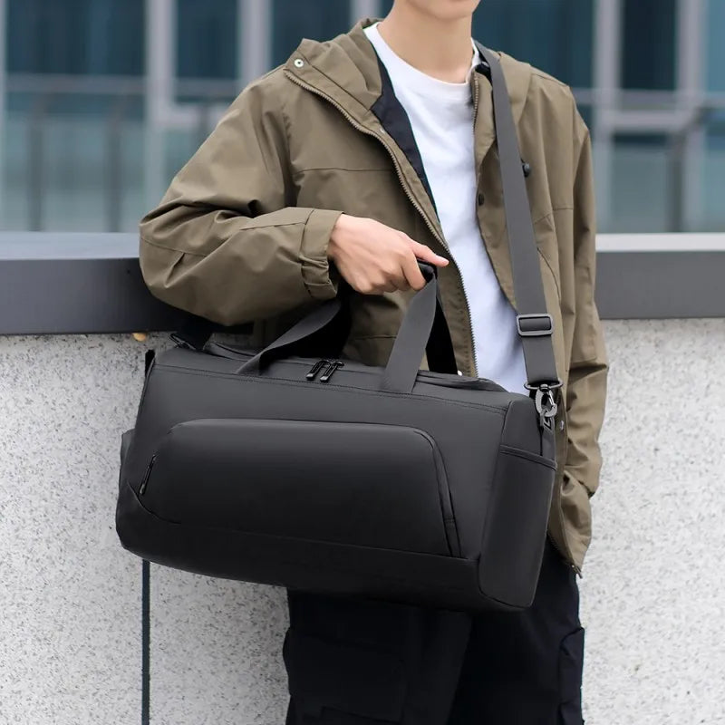 Person holding a black shoulder bag outdoors
