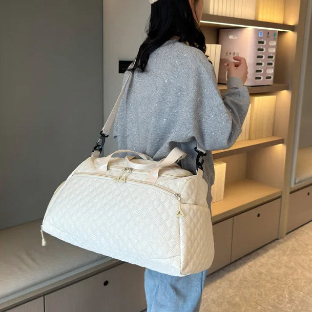 Person holding a white quilted bag in a modern interior setting